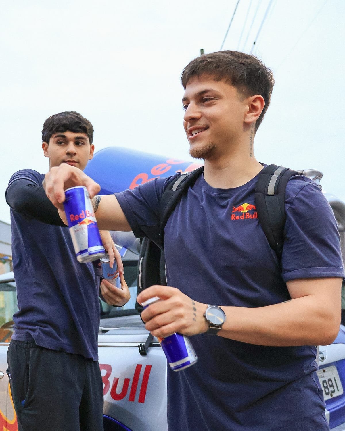 Arthur Lacerda sorrindo, de camisa azul-marinho com o logo da Red Bull, segurando uma lata, em pé.